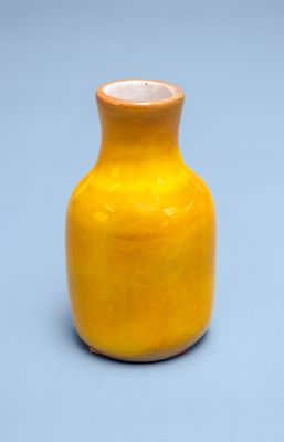 a small yellow vase sitting on a blue surface