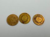 trois types différents de pièces d'or sur une surface blanche