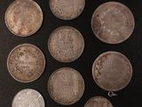 six different types of silver coins on a black surface