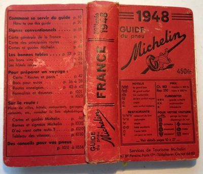 an old book with a red cover sitting on top of a table