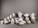 une image représentant un ensemble d'assiettes et de tasses blanches et argentées