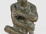 bronze statue of a man sitting on the ground with his hands on his knees