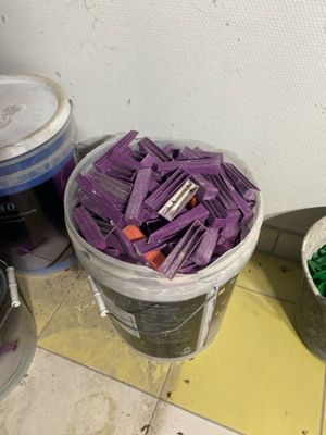 two buckets of purple paint and two buckets of green paint on the floor