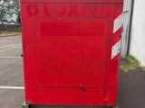 a red box sitting in a parking lot next to a building