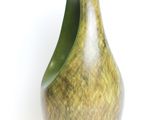 a green vase that is sitting on a white surface