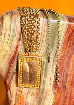 a necklace with a picture of a man on it on a mannequin