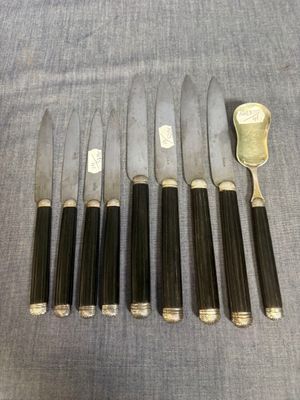 six couteaux et une cuillère posés sur une table