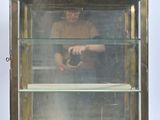 une vitrine en verre dans laquelle se trouve un homme tenant un appareil photo
