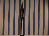 statue of a man standing on a pedestal in front of a striped wall
