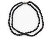 un gros plan d'un collier de perles noires sur fond blanc