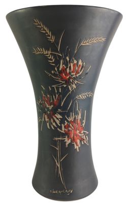 a black vase with red flowers on it on a white background