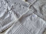 four white linen napkins with embroidered designs on them sitting on a table