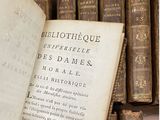 un vieux livre posé sur une table en bois, à côté d'une pile de livres