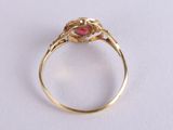 a close up of a gold ring with a red stone in it