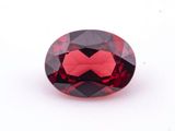a close up of a red garnet stone on a white surface