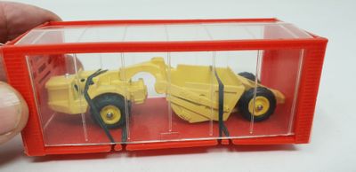 quelqu'un tient un camion miniature à l'intérieur d'un conteneur rouge