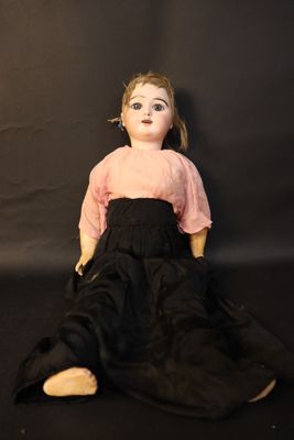an old doll is sitting on a black surface with a black background