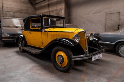 une voiture jaune et noire dans un garage, à côté d'autres voitures