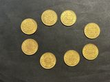 six pièces d'or disposées en cercle sur une surface noire
