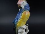 a figurine of a parrot sitting on a tree branch