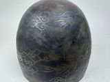 a black vase with designs on it on a white surface