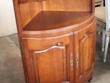 a corner cabinet with a tv on top of it next to a table