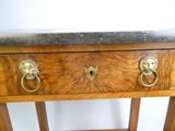 une table en bois avec un plateau en marbre surmonté de deux têtes de lion en laiton