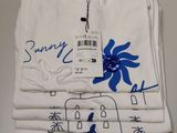 trois t-shirts blancs ornés de fleurs bleues sont empilés les uns sur les autres
