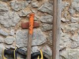 un seau contenant des outils de jardinage posé à côté d'un mur de pierre