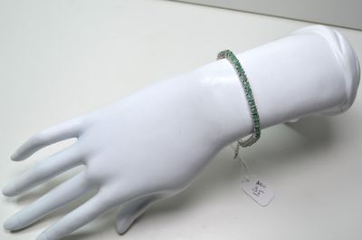 une main de mannequin blanche à laquelle est enfilé un bracelet vert