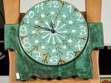 a green clock on top of a wooden stand in a kitchen