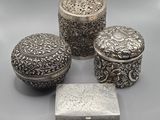 trois boîtes en argent et une boîte avec un couvercle posées sur une table
