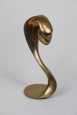 brass sculpture of a bird on a stand against a white background