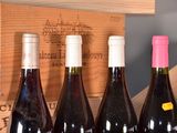 several bottles of wine are lined up in a row in front of a wooden box