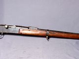 Un vieux fusil est posé sur une surface blanche, dans un étui vert.