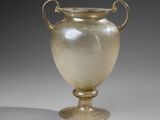 a glass vase sitting on a pedestal on a gray surface