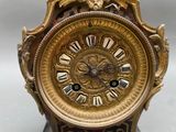 a gold clock with roman numerals on the face