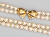 un gros plan sur un collier orné de perles et d'un nœud