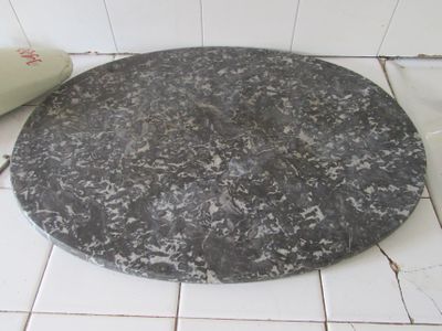 une assiette en marbre noir et blanc posée sur un sol carrelé