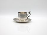 a silver cup and saucer on a saucer on a white surface