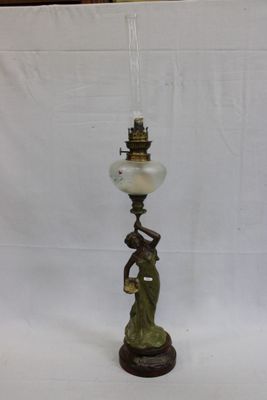 une lampe à l'ancienne représentant une femme tenant un abat-jour en verre