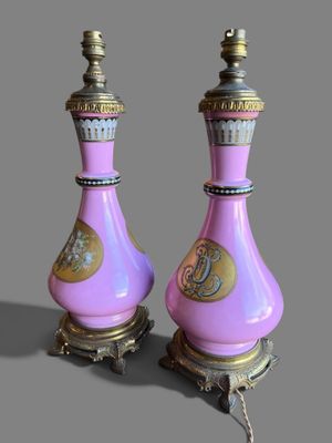 une paire de vases roses et dorés posés sur un socle, sur fond gris