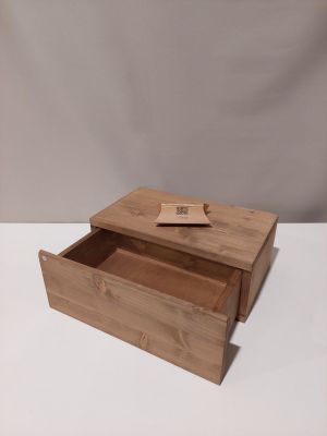 une petite boîte en bois dont le couvercle est ouvert, posée sur une surface blanche