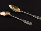 pair of silver spoons on a black surface with a black background