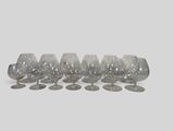 six empty wine glasses lined up on a white surface