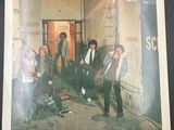 the album cover of a group of men standing in front of a building
