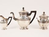 three pieces of silver tea and coffee set on a white surface