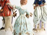 three figurines of people dressed in historical clothing and hats