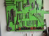 many tools hanging on a green board in a garage