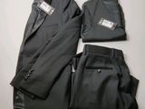 deux pièces d'un costume noir et un pantalon posés sur une surface blanche